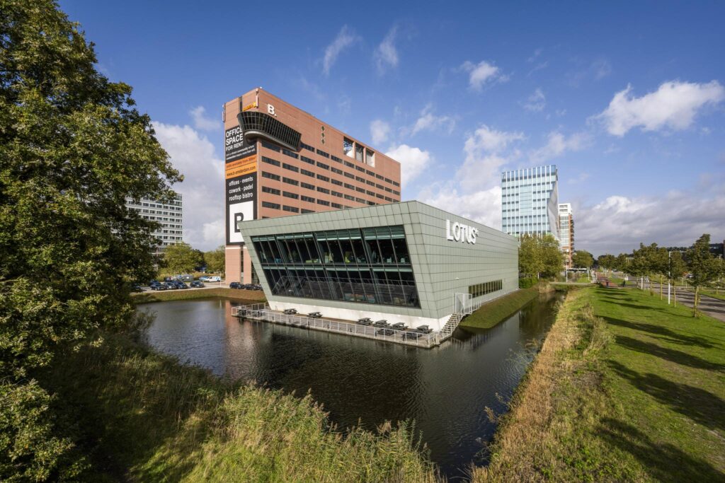 Modern kantoorgebouw van Lotus aan de Johan Huizingalaan in Amsterdam, gelegen aan het water met omliggende hoogbouw.
